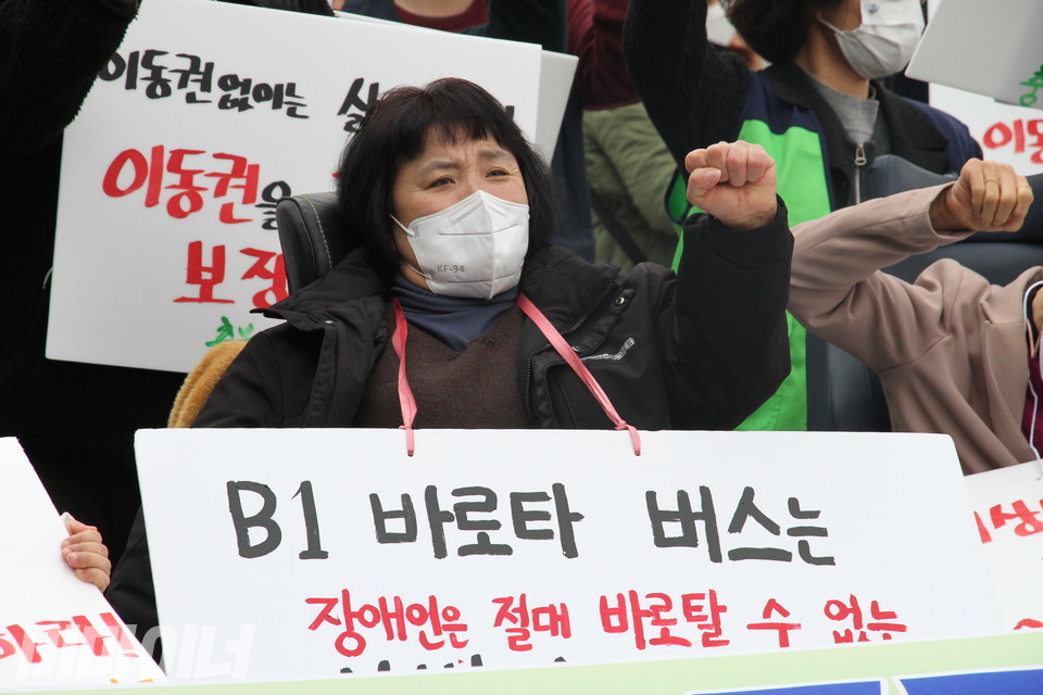 문경희 세종장애인차별철폐연대 공동대표가 ‘투쟁’을 외치고 있다. ‘B1 바로타 버스는 장애인은 절대 바로 탈 수 없는 버스’라고 적힌 피켓을 목에 걸었다. 사진 하민지