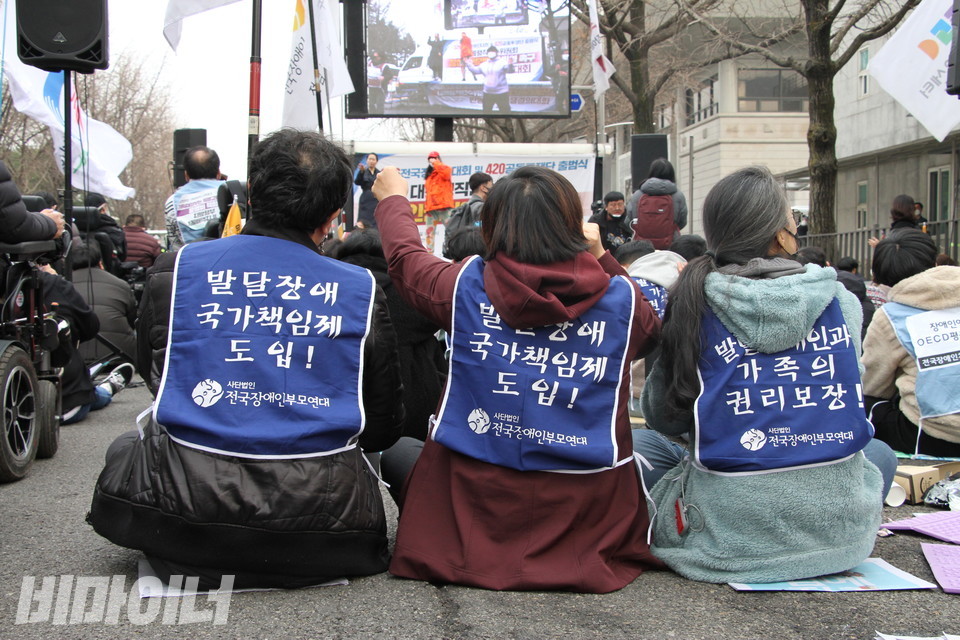 “발달장애 국가책임제 도입”이라고 적힌 몸피켓을 입은 사람들의 뒷모습. 사진 하민지 