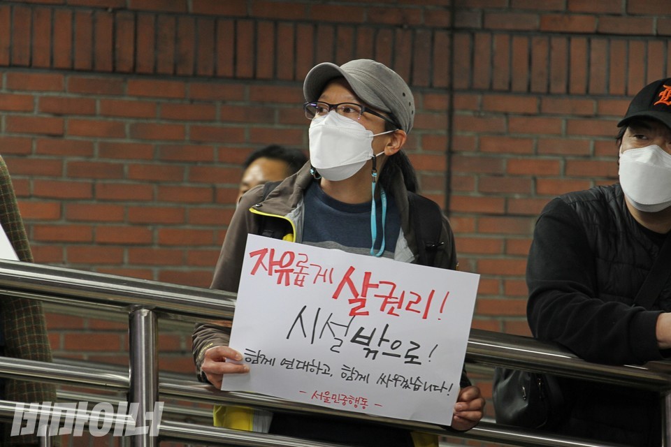서울민중행동 활동가가 ‘자유롭게 살 권리! 시설 밖으로! 함께 연대하고 함께 싸우겠습니다!’라고 적은 피켓을 들고 있다. 사진 하민지