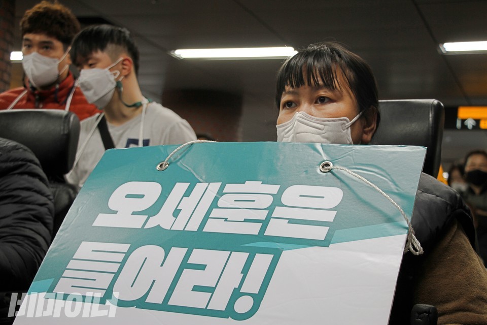 한 활동가가 ‘오세훈은 들어라!’라고 적힌 피켓을 목에 걸고 있다. 사진 하민지