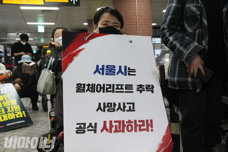 한 활동가가 “서울시는 휠체어 리프트 추락 사망사고 공식 사과하라!”고 적힌 피켓을 들고 있다. 사진 이슬하