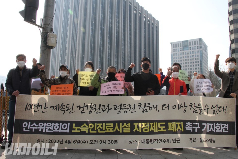 기자회견 현장. 참가자들이 구호를 외치고 있다. 현수막에는 ‘10년간 계속된 건강권과 평등권 침해, 더 이상 참을 수 없다! 인수위원회의 노숙인 진료시설 지정제도 폐지 촉구 기자회견’이라 적혀 있다. 사진 하민지