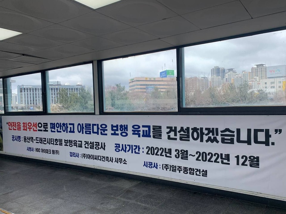 기존 공중보행교 내에 설치된 현수막. ‘안전을 최우선으로 편안하고 아름다운 보행 육교를 건설하겠습니다. 공사명 용산역-드래곤시티호텔 보행육교 건설공사. 공사기간 2022년 3월~2022년 12월. 시행사 HDC아이파크몰(주), 감리사 (주)아이씨디건축사사무소, 시공사 (주)일주종합건설’이라 적혀 있다. 사진 홈리스행동