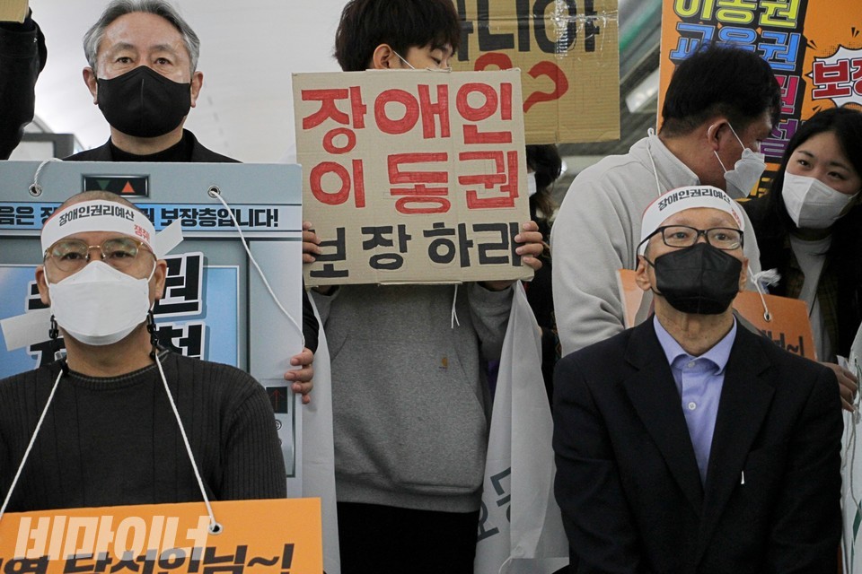 삭발을 마친 이우연 양주디딤돌장애인자립생활센터 소장(왼쪽)과 김태현 사무국장(오른쪽). 가운데에는 ‘장애인 이동권 보장하라’라고 적힌 피켓이 보인다. 사진 이슬하