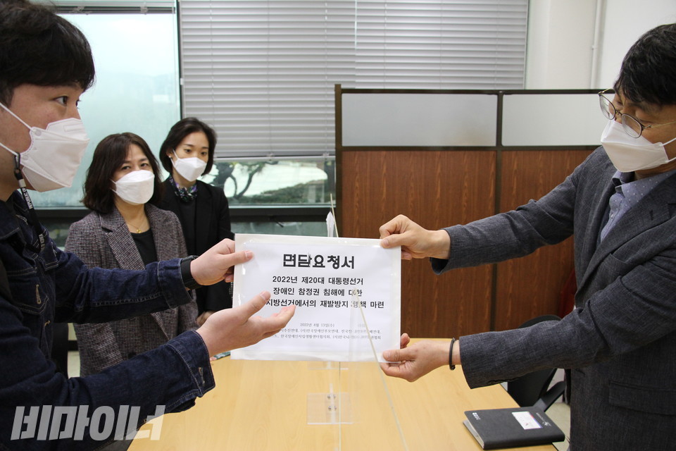 김대범 피플퍼스트 활동가가 중앙선관위 직원에게 면담요청서를 전달하고 있다. 사진 이슬하