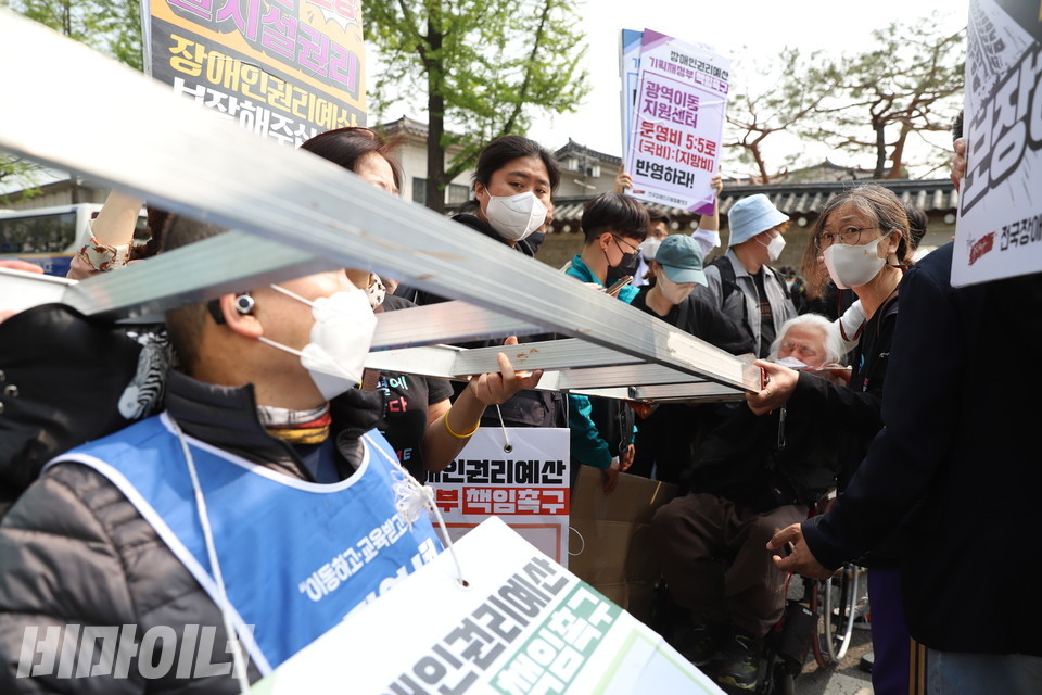 삭발 투쟁 후 마무리 집회를 위해 이동하던 중 도로를 점거한 장애인 활동가들. 사다리로 서로의 몸을 묶었다. 사진 강혜민 
