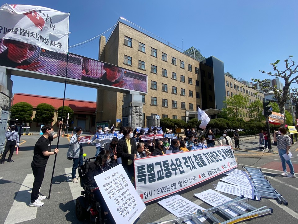 충청북도청 앞 기자회견 현장. 50여 명의 활동가들이 참석했다. 현수막에는 ‘특별교통수단 격차 철폐 기자회견’이라 적혀 있고 그 앞에 사다리가 놓여 있다. 사진 전장연