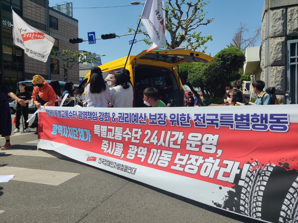 충북장차연 깃발이 휘날리고 있다. 그 아래 현수막에는 ‘장애인특별교통수단 광역책임 강화&권리예산 보장 위한 전국특별행동, 광역자치단체가 특별교통수단 24시간 운영, 즉시콜, 광역이동 보장하라!’라고 적혀 있다. 사진 전국장애인야학협의회