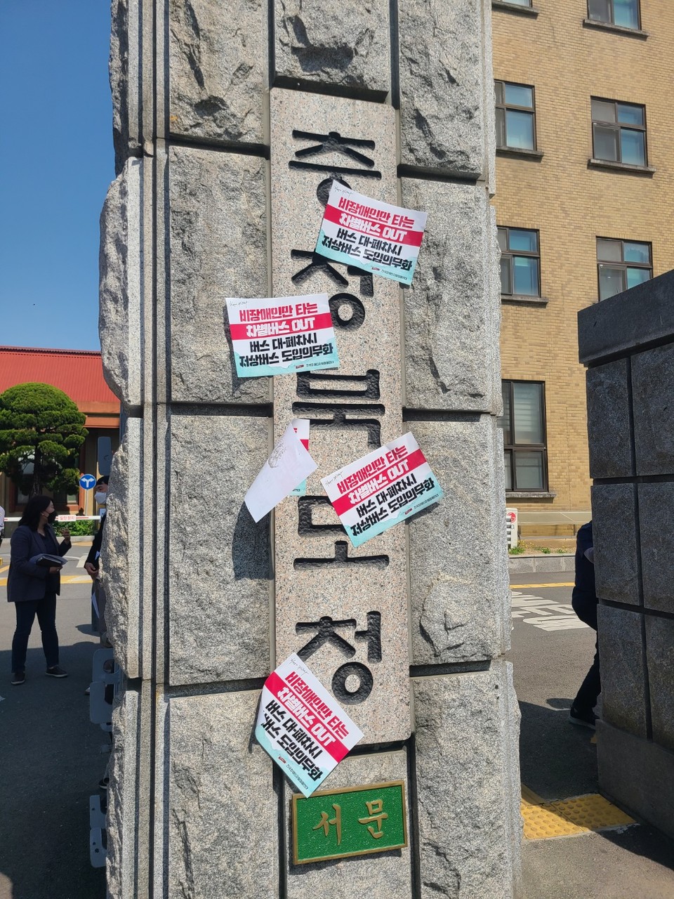 충청북도청 현판 앞에 붙은 피켓들. ‘비장애인만 타는 차별버스 OUT, 버스 대폐차 시 저상버스 도입 의무화’라고 적혀 있다. 사진 전장야협