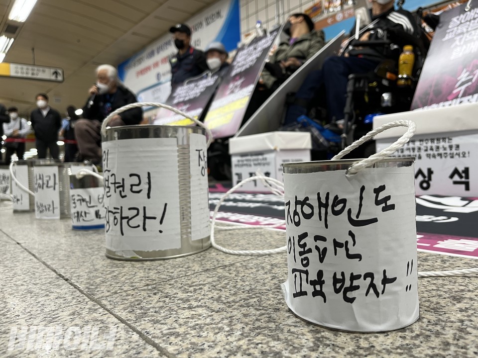 오전 8시, 삼각지역에서 김지훈·장상석 의정부장애인자립생활센터(아래 의정부센터) 활동가가 삭발투쟁을 진행했다. 이어 박경석 전장연 대표와 김영란 의정부센터 활동가가 오체투지를 하며, 지하철 선전전을 벌였다. 지하철 선전전을 앞두고 활동가들이 발언하고 있다. 그 앞에는 '장애인도 이동하고 교육받자'라는 글이 쓰여 있는 깡통이 놓여 있다. 사진 허현덕