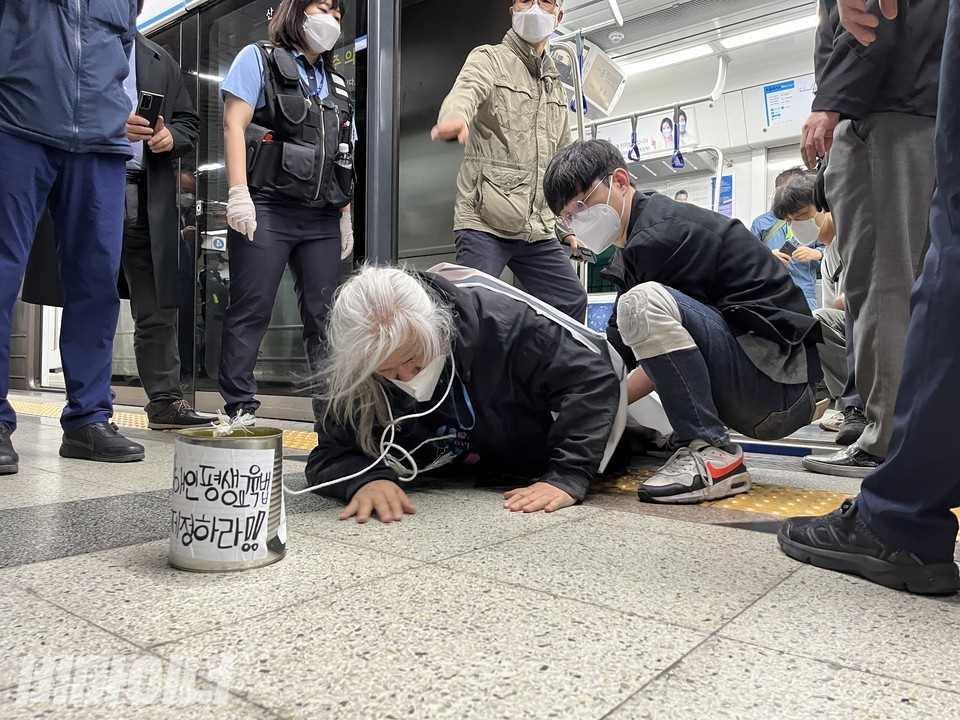 박경석 전장연 대표가 지하철에서 힘겹게 내리고 있다. 그의 목에는 '장애인평생교육법 제정하라'라는 글이 쓰여 있는 깡통이 묶여 있다. 사진 허현덕