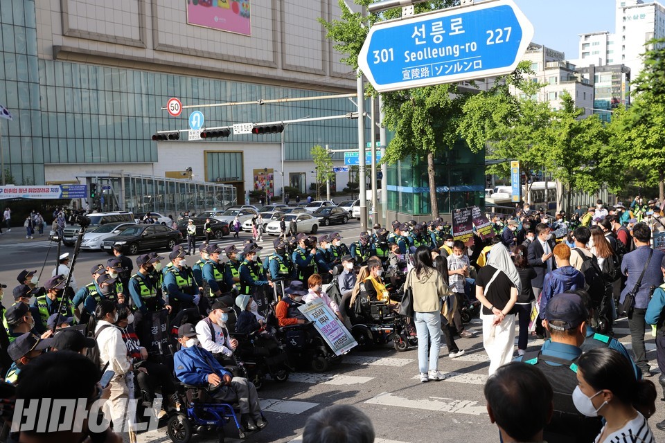 한티역 인근 횡단보도를 점거한 활동가들. 경찰 수십 명이 활동가들을 막아서고 있다. ‘선릉로’라고 적힌 표지판이 보인다. 사진 하민지