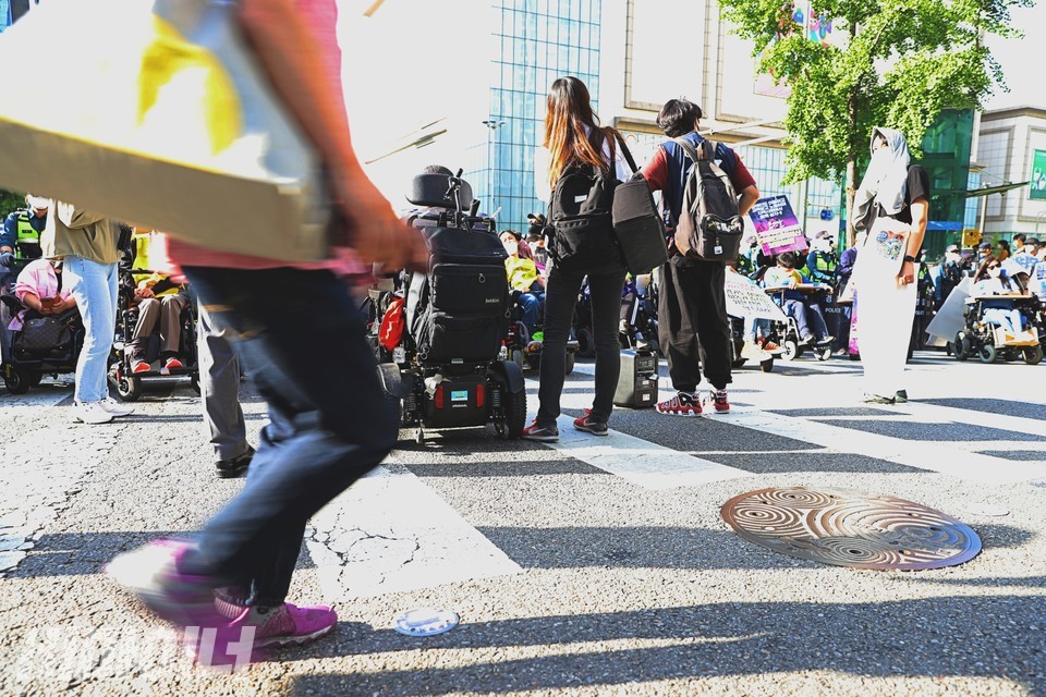 이형숙 서울시협의회 회장이 발언하고 있고, 그 뒤를 한 사람이 걸어서 지나가고 있다. 사진 하민지