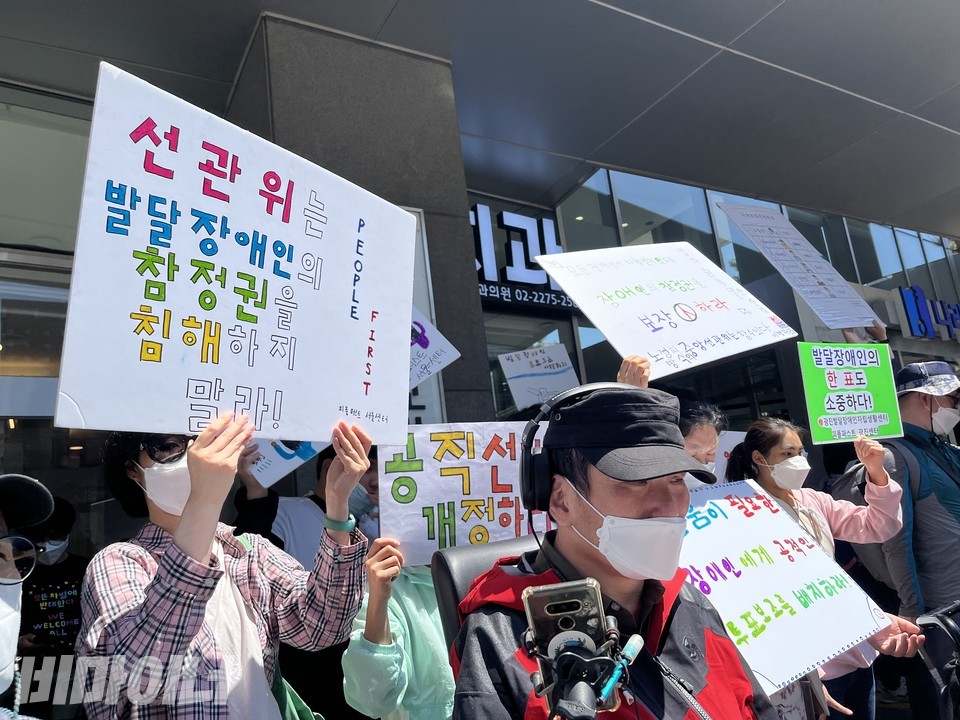 기자회견 참가자가 “선관위는 발달장애인의 참정권을 침해하지 말라!”고 적힌 손피켓을 들고 있다. 사진 허현덕