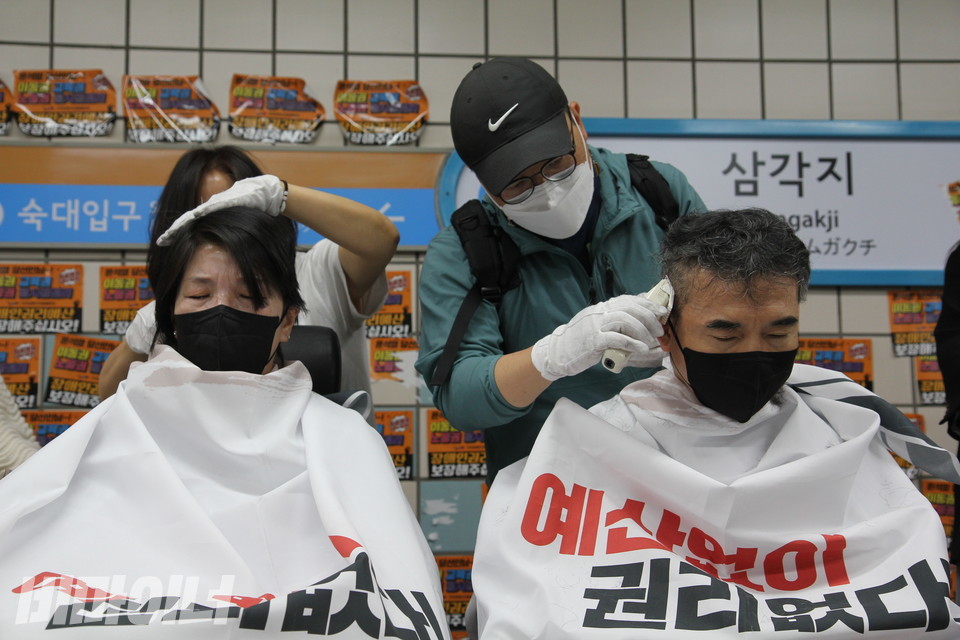 박길연 교장과 문상민 민들레장애인야학 사무국장이 나란히 앉아 삭발을 하고 있다. 사진 이슬하