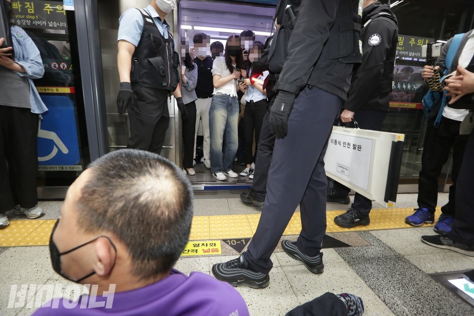 한성대입구역에 멈춘 지하철의 문이 열리자, 안에 타 있던 승객들이 승강장에 주저앉아 있는 신경수 팀장의 모습을 보고 놀라고 있다. 사진 이슬하