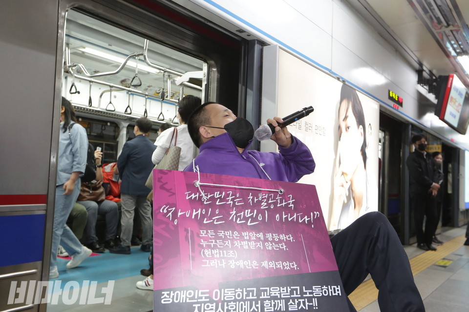 혜화역에 도착한 신경수 팀장이 발언하고 있다. 그의 목에는 “대한민국은 차별공화국. 장애인은 천민이 아니다! 장애인도 이동하고 교육받고 노동하며 지역사회에서 함께 살자!”라고 적힌 피켓이 걸려 있다. 사진 이슬하