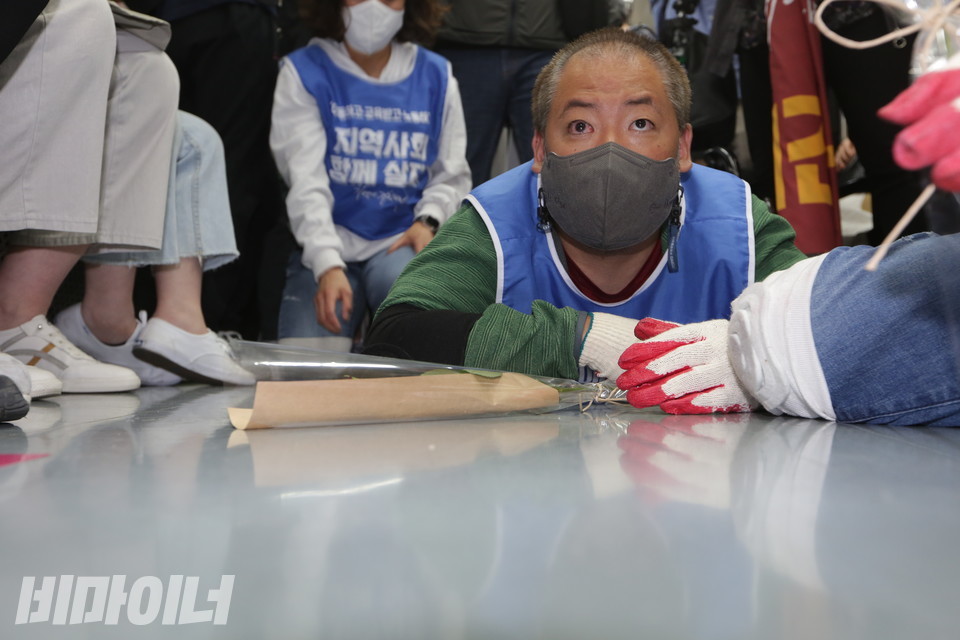 장애인 활동가가 “이동하고 교육받고 노동하고 지역사회 함께 살자”고 적힌 몸피켓을 입고 지하철 오체투지를 하고 있다. 그의 앞에 장미꽃 한 송이가 놓여 있다. 사진 강혜민