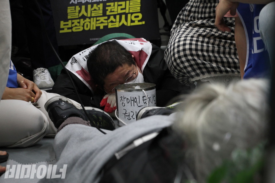 지하철 오체투지를 하는 이형숙 대표. 그의 뒤로 “탈시설 권리를 보장해주십시오”라는 문구가 보인다. 사진 강혜민