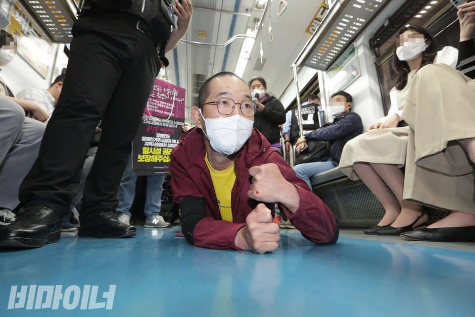 이상진 노동자가 지하철 바닥에 엎드려 있다. 손등이 까져 피가 나고 있다. 사진 이슬하