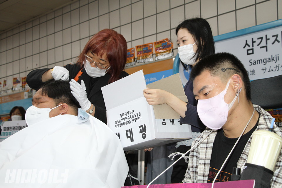 김대광 활동가가 삭발하고 있다. 그 옆에 유진우 노들장애인자립생활센터 활동가가 고개를 숙인 채 생각에 잠겨 있다. 그 역시 지난달 12일 삭발투쟁에 참여했다. 사진 이슬하 