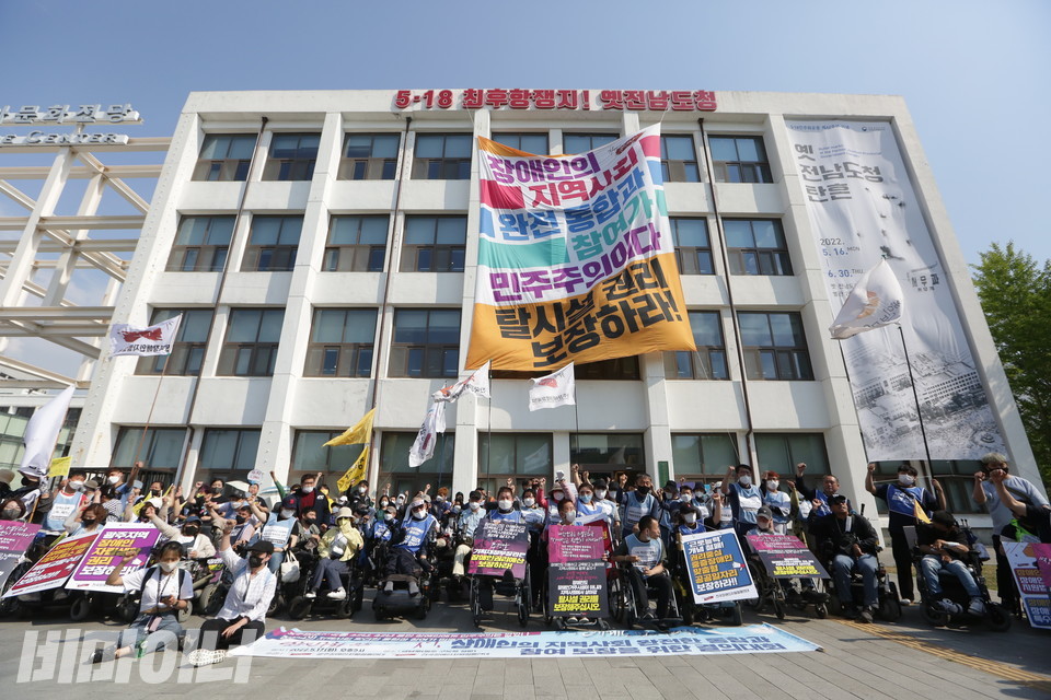 “5·18 최후항쟁지! 옛 전남도청”이라고 적힌 건물 외벽에 대형 현수막이 걸려 있다. 현수막에는 “장애인의 지역사회 완전 통합과 참여가 민주주의다. 탈시설권리 보장하라!”고 적혀 있다. 건물 앞에 수많은 활동가들이 투쟁을 외치고 있다. 사진 이슬하
