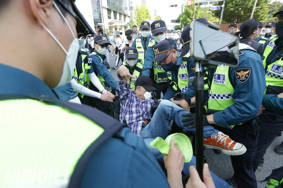 경찰이 휠체어 탄 장애인 활동가를 진압하고 있다. 사진 이슬하