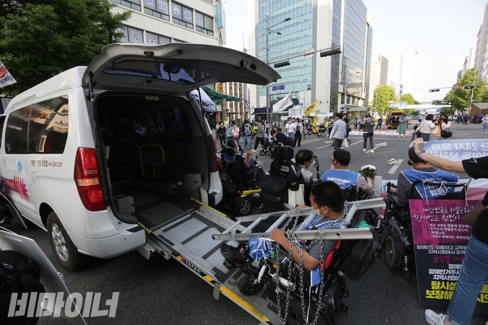 배영준 광주장애인차별철폐연대 상임활동가가 사다리와 쇠사슬을 목에 건 채 새빛콜 리프트 위에 올라가 있다. 사진 이슬하