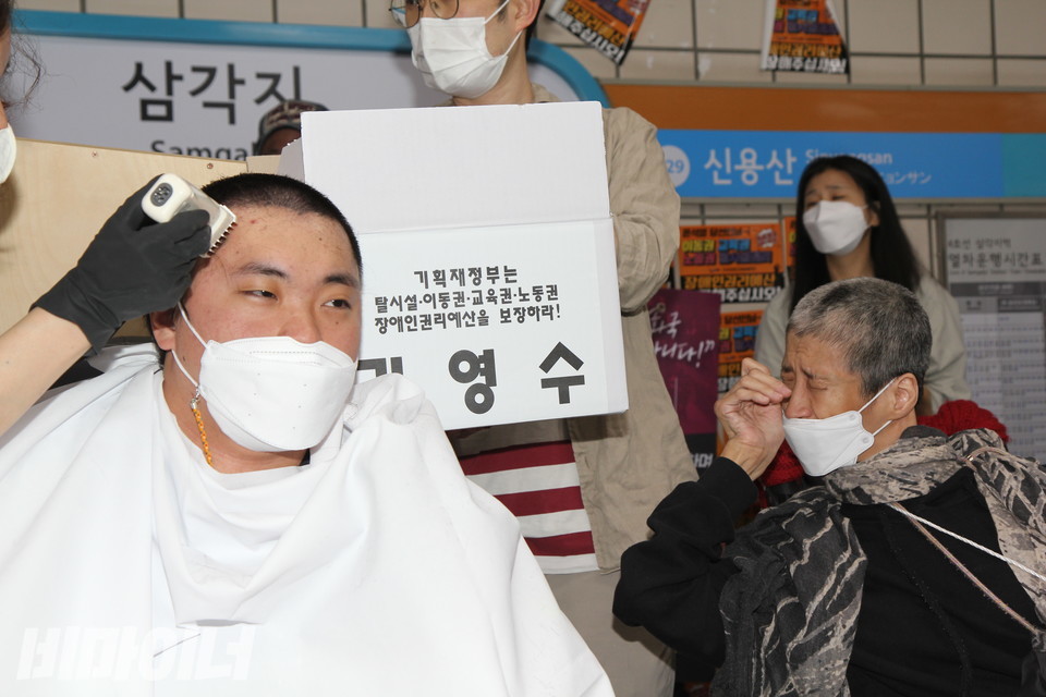 김영수 활동가가 삭발하는 모습을 보고, 같은 성동장애인자립생활센터의 최진영 활동가가 눈물을 훔치고 있다. 그 역시 지난달 27일 삭발해 머리가 짧다. 사진 이슬하 