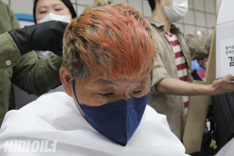 삭발식에 임하는 임종운 성동장애인자립생활센터 활동가가 고개를 숙이고 있다. 주황빛으로 물든 그의 머리가 눈에 띈다. 사진 이슬하