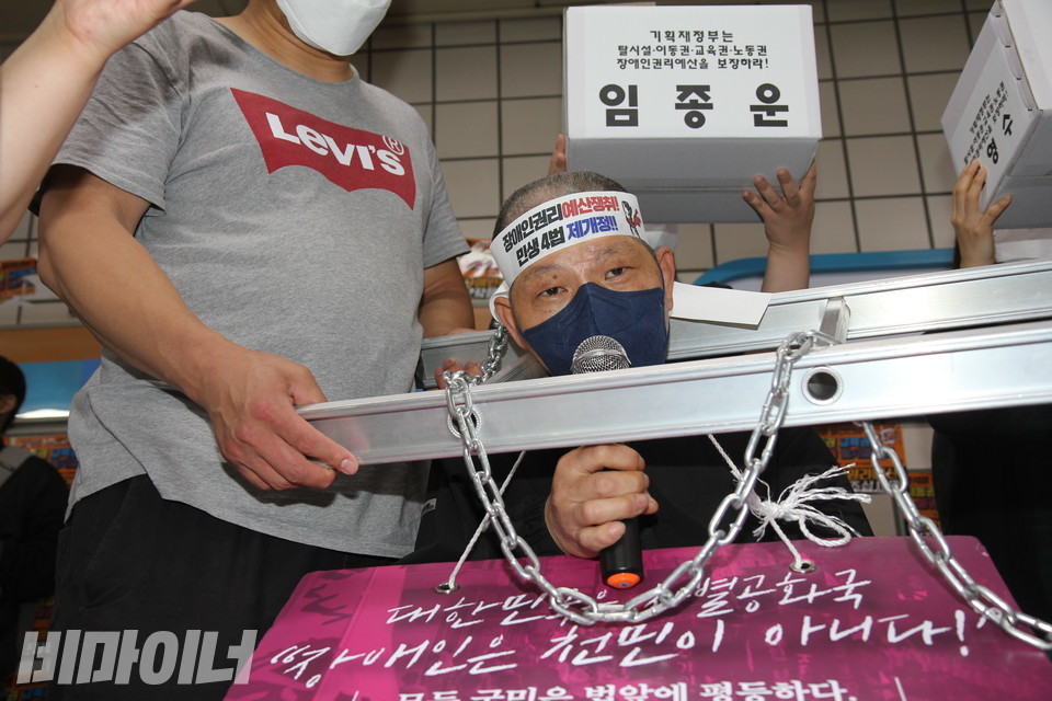 임종운 활동가가 쇠사슬이 달린 사다리를 목에 건 채 발언하고 있다. 사진 이슬하
