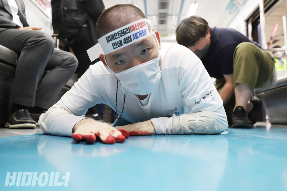 삭발한 이상도 활동가가 오체투지를 하고 있다. 이마에는 “장애인권리예산 쟁취! 민생 4번 제개정!”이라고 적힌 띠를 두르고 있다. 사진 강혜민