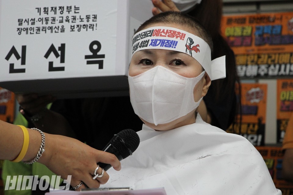 삭발을 마친 신선옥 소장이 “장애인권리예산 쟁취! 민생4법 제개정!”이라고 적힌 띠를 머리에 두르고 발언하고 있다. 사진 하민지