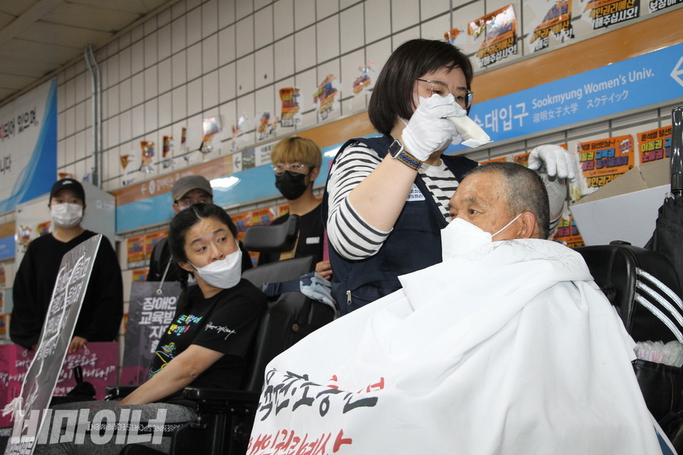 김홍기 노동자가 삭발하는 모습을 조상지 노들장애인야학 학생이 바라보고 있다. 사진 이슬하