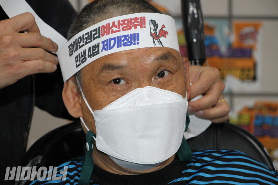 삭발을 마친 김홍기 노동자가 머리에 “장애인권리예산 쟁취! 민생4법 제개정!”이라고 적힌 띠를 두르고 있다. 사진 이슬하