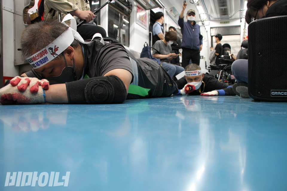 배재현 서울장애인차별철폐연대 대의원(앞)과 김민석 진주장애인자립생활센터 소장이 지하철 바닥을 기었다. 김 소장은 마이크를 잡고 시민들을 향해 장애인권리보장예산의 중요성을 알렸다. 사진 허현덕 