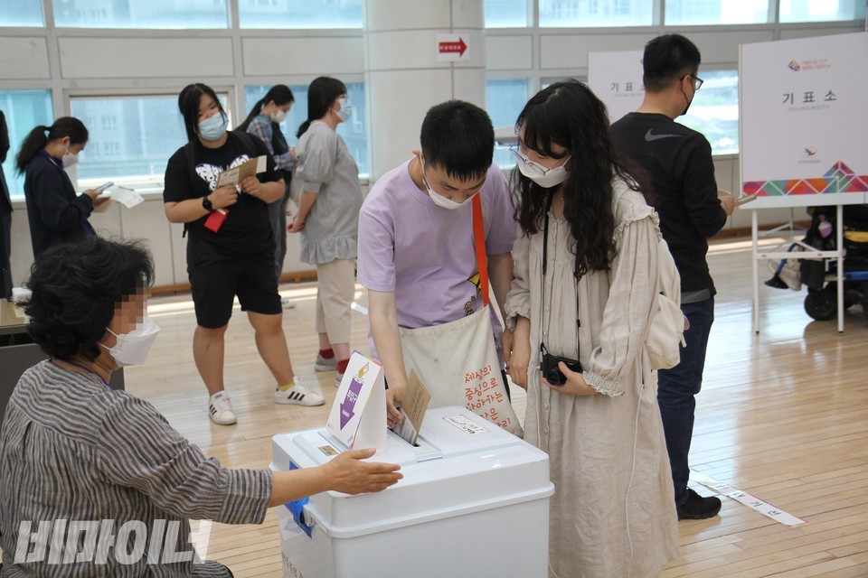 김동옥 씨가 투표함에 투표용지가 담긴 봉투를 넣고 있다. 그의 옆에 투표보조인이 서 있다. 사진 이슬하
