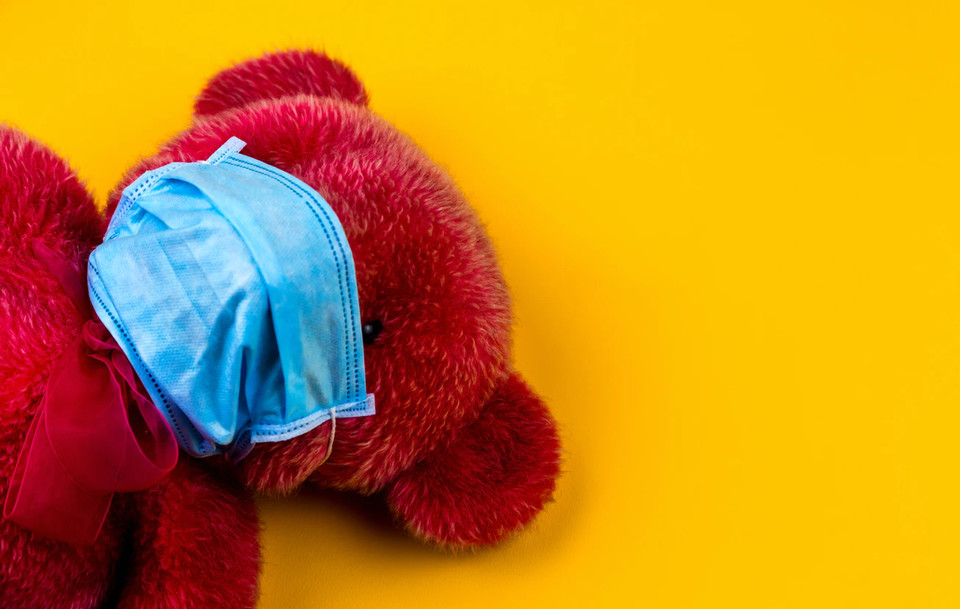 노란색 배경에 빨간 곰인형이 마스크를 쓰고 누워 있다. 사진 언스플래시