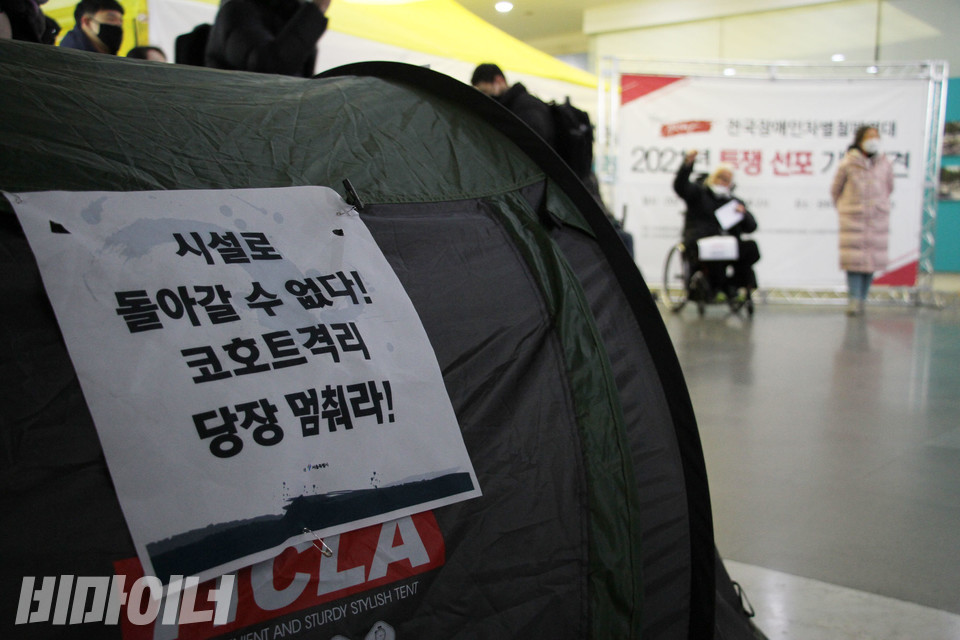 지난해 1월, 전국장애인차별철폐연대가 광화문 해치마당에서 신년 투쟁 선포식을 열고 있다. 신아원 코호트 격리 중단을 촉구하는 텐트에는 '시설로 돌아갈 수 없다! 코호트격리 당장 멈춰라!'라는 피켓이 붙어 있다. 사진 강혜민 