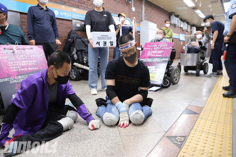 서권일 활동가가 오체투지를 하기 위해 휠체어에서 내렸다. 그 옆에는 박경수 민들레장애인자립생활센터 활동가가 함께 휠체어에서 내려 대기하고 있다. 