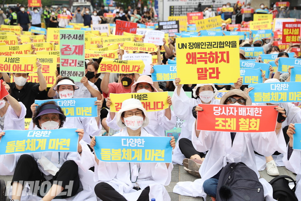 거주시설부모회 소속 사람들이 소복을 입고 “거주시설 존재, 권리로 인정하라” “당사자 배제한 조례 철회” “유엔장애인권리협약을 왜곡하지 말라” “다양한 돌봄 체계 마련”이라고 적힌 손피켓을 들고 있다. 사진 강혜민