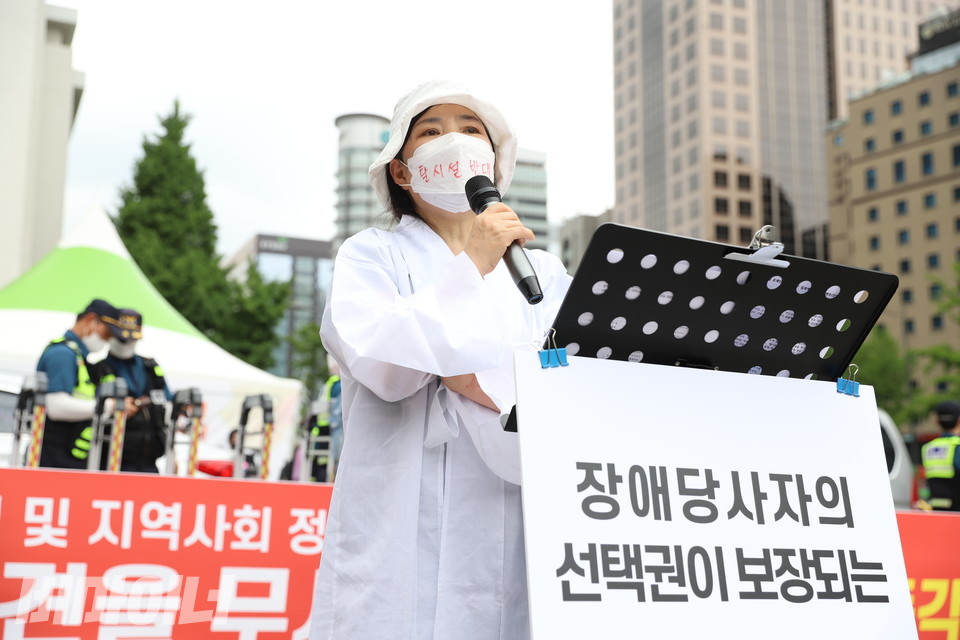 김현아 거주시설부모회 대표가 소복을 입고 발언하고 있다. 하얀 마스크에는 빨간 글씨로 “탈시설 반대”라고 적혀 있다. 사진 강혜민