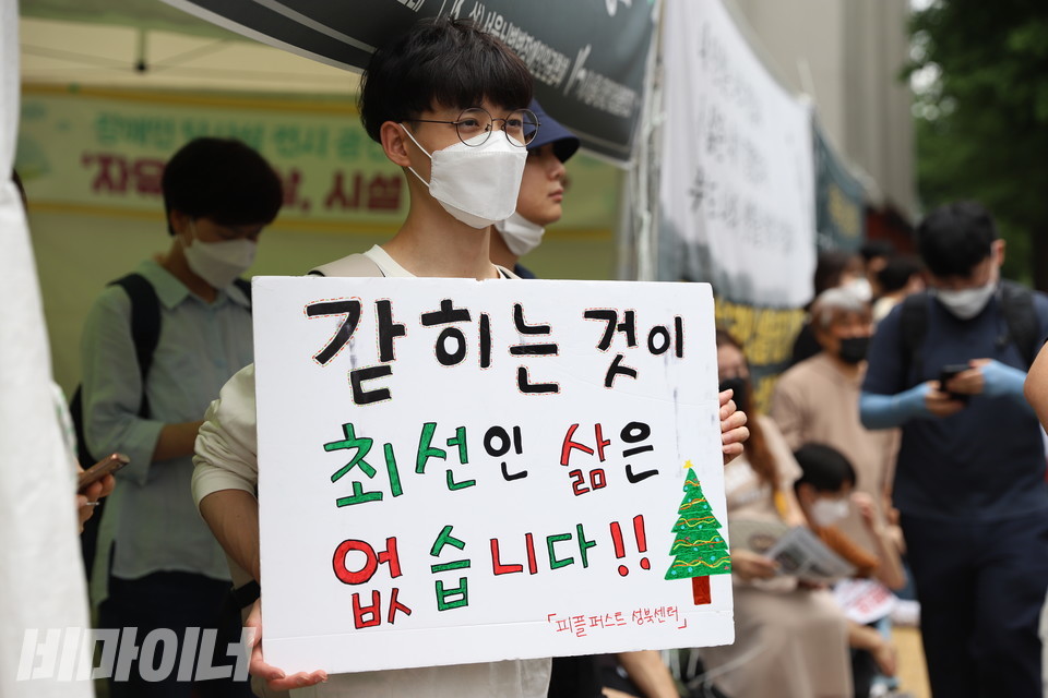 피플퍼스트성북센터 활동가가 “갇히는 것이 최선인 삶은 없습니다”라고 적힌 피켓을 들고 있다. 사진 강혜민