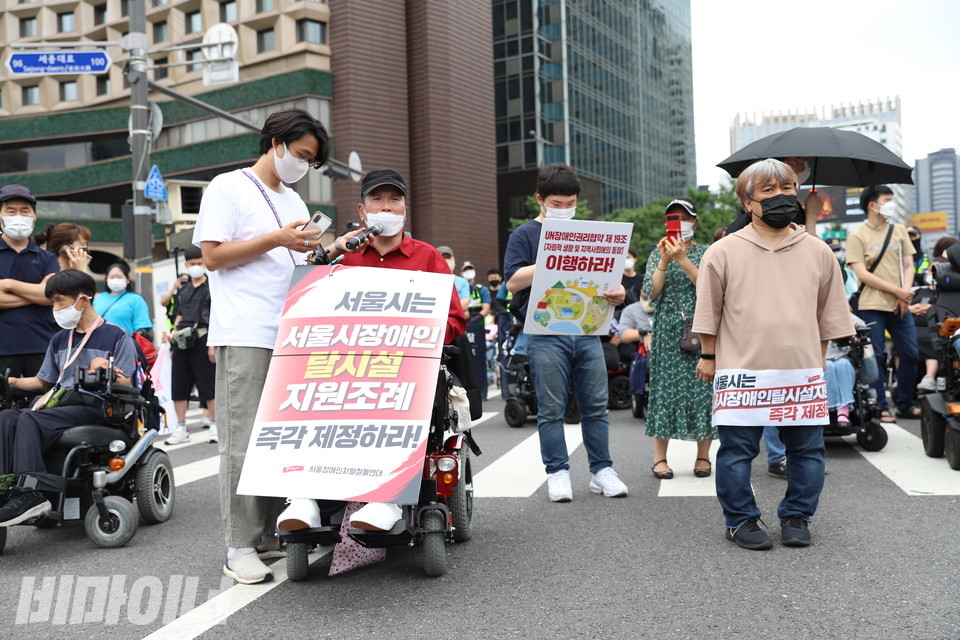추경진 노들장애인자립생활센터 권익옹호 활동가가 세종대로를 점거한 채 탈시설조례 제정을 촉구하는 발언을 하고 있다. 그의 앞엔 “서울시는 서울시 장애인탈시설지원조례 즉각 제정하라”고 적힌 피켓이 있다. 사진 강혜민 