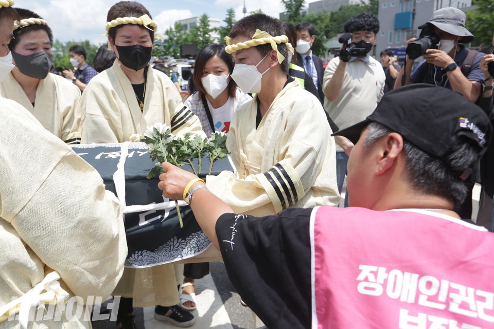 문경희 세종장애인차별철폐연대 공동대표가 손을 뻗어 상여 위에 헌화하고 있다. 사진 이슬하