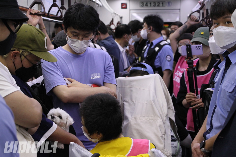 사람들로 붐비는 지하철 안. 활동가들과 지하철 보안관, 승객들이 뒤섞여 있다. 문애린 이음장애인자립생활센터 소장이 다른 활동가 품 안에 안긴 강아지를 바라보고 있다. 사진 이슬하