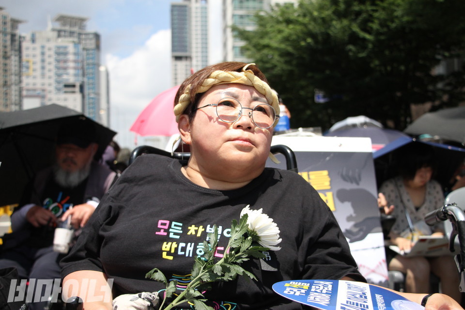 박김영희 장애인차별금지추진연대 상임대표가 국화를 든 채 장례식 발언을 듣고 있다. 사진 이슬하