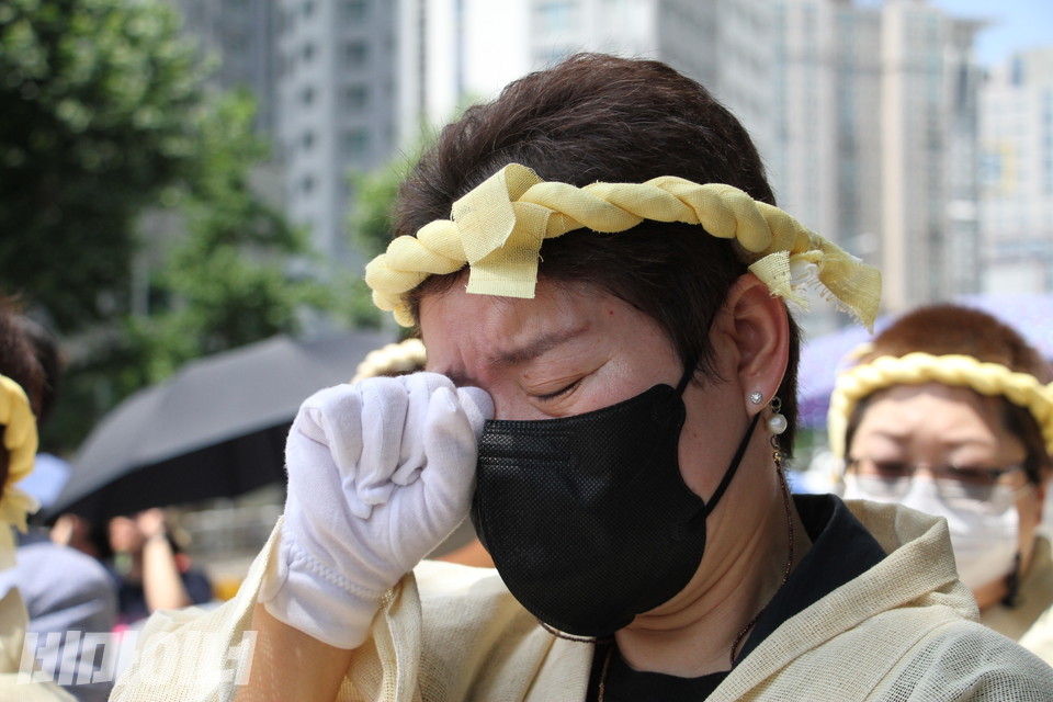 장애인 자녀를 둔 어머니가 눈물을 훔치고 있다. 그는 상복을 입고 있다. 사진 이슬하