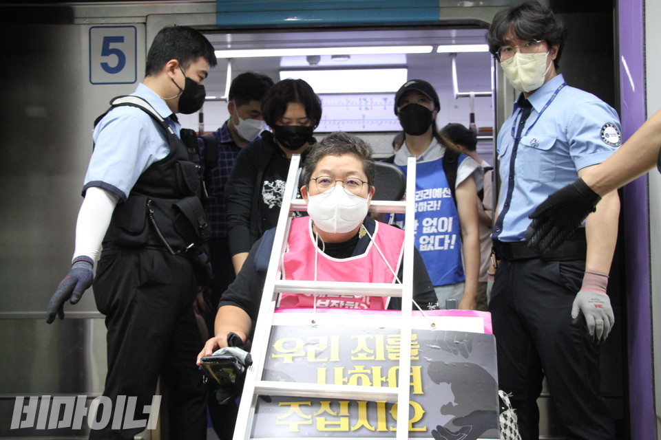 이형숙 서울시장애인자립생활센터협의회 회장이 비장한 표정으로 지하철에서 내리고 있다. 그의 목에는 사다리와 함께, “우리 죄를 사하여 주십시오”라고 적힌 피켓이 걸려 있다. 사진 이슬하