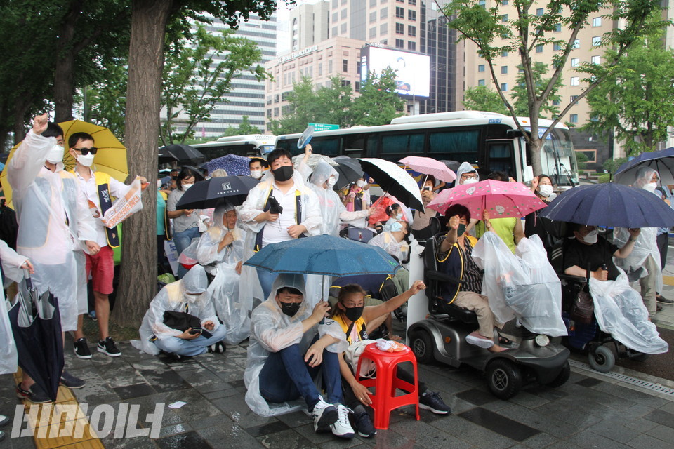 결의대회에 참석한 활동가들이 ‘투쟁’을 외치고 있다. 결의대회 도중 갑자기 소나기가 와서 활동가들이 우의를 입고 우산을 썼다. 사진 하민지